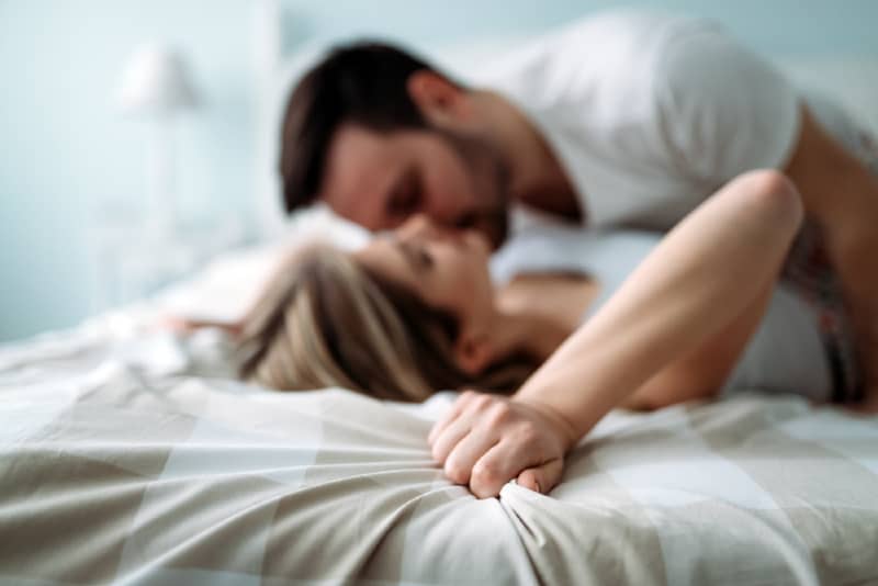 man and woman kissing while lying on bed