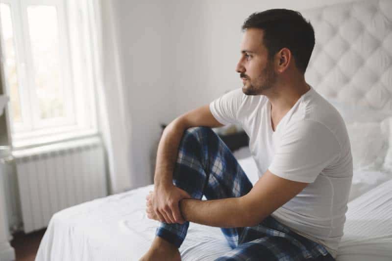 unhappy man in pajamas on bed