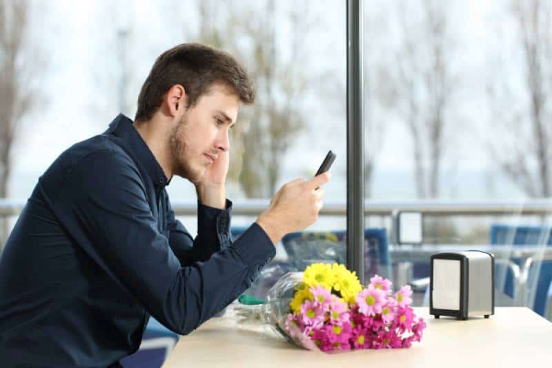 man looking at phone unhappy