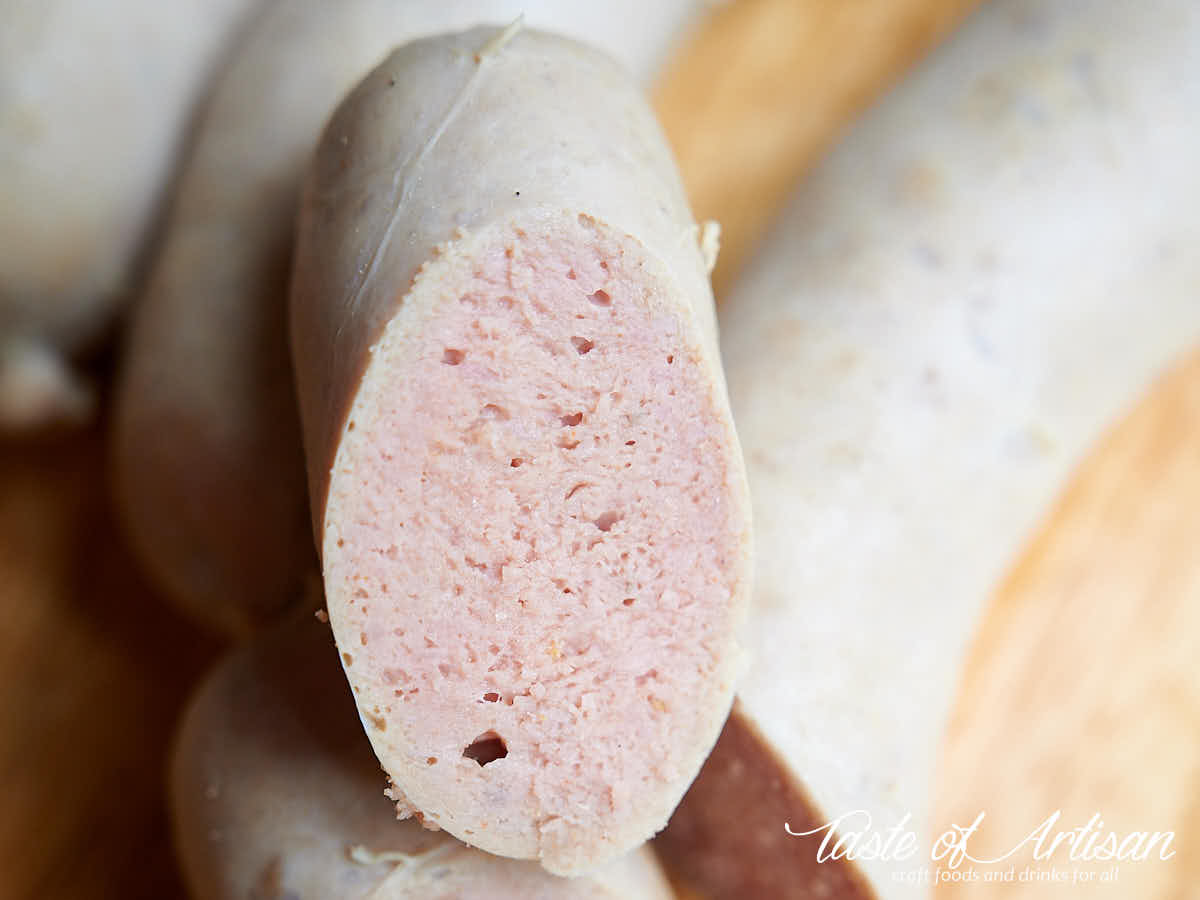 Top-down image of four links of bockwurst smoked sausage on brown palette.