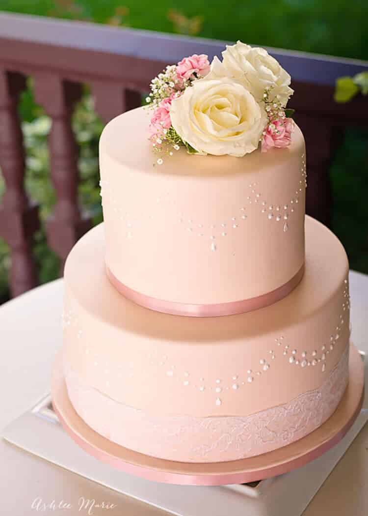 A lovely pastel pink wedding cake with royal icing. Video tutorial on how to use stencils to make this dish quickly and easily