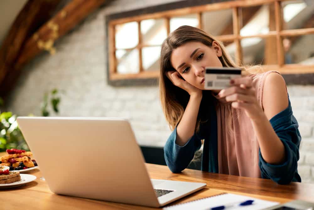 Young sad woman having problems while using credit card