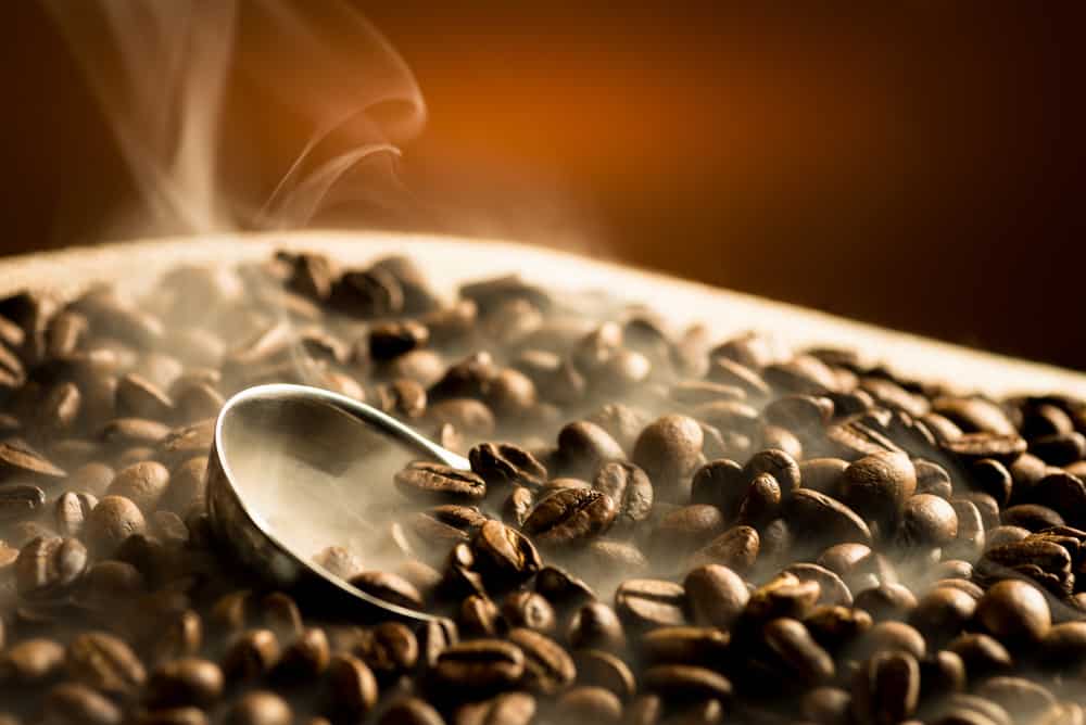 Roasting coffee beans with smoke on dark background
