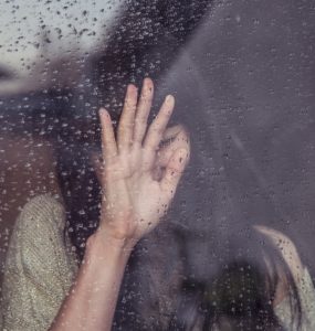 woman crying in the window in the rain