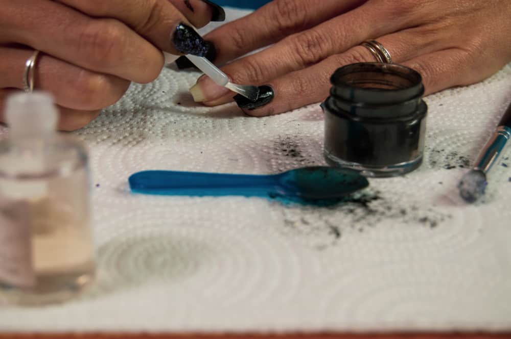 Woman applying a top coat to dipped fingernails