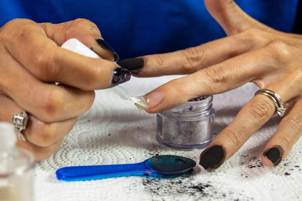 Woman putting base coat on her nails before dipping them in dip powder