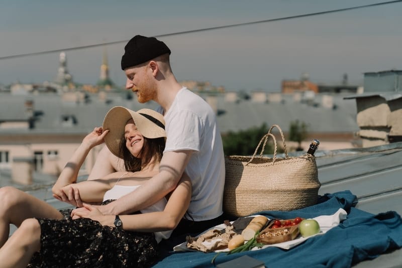 man in white t-shirt and woman having picnic on rooftop