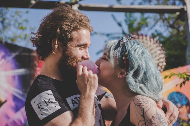 smiling man and woman biting pink cotton candy