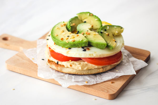 Chopsticks with an English muffin with slices of hummus, eggs and butter.