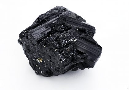 Woman's hand holding dark, powerful tourmaline crystal in healing concept