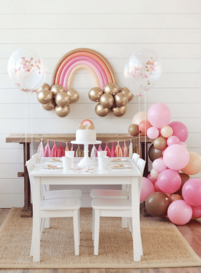 balloon garland and childs party set up with white table and cake