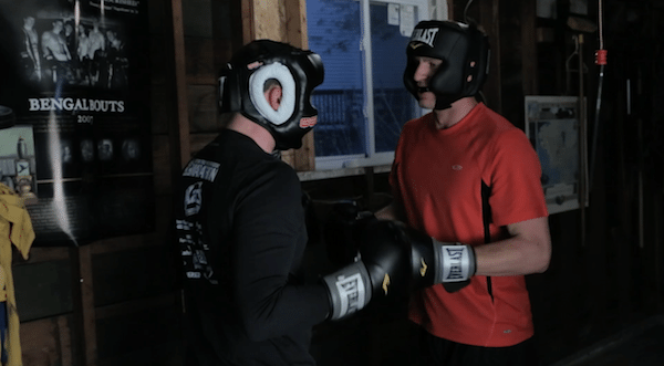 Two men fighting in a club fight in a garage.
