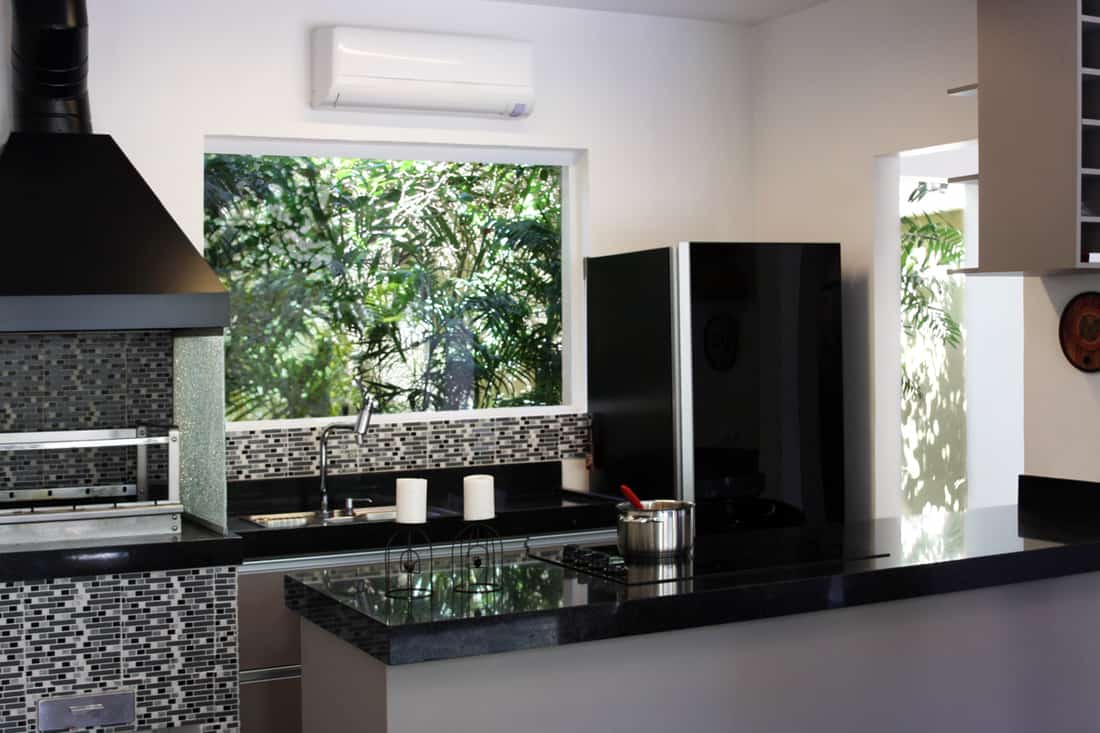 A classic modern kitchen with wood vinyl flooring, black granite countertops and white cabinet panels