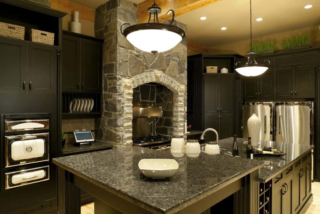 Kitchen with marble countertops, faux stone wall decor and black cabinets