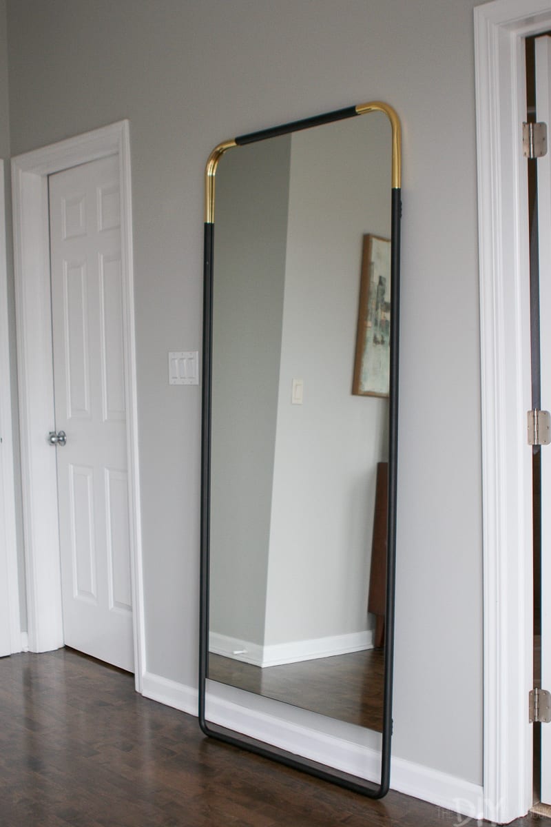 Master bedroom with black and gold full length mirror.