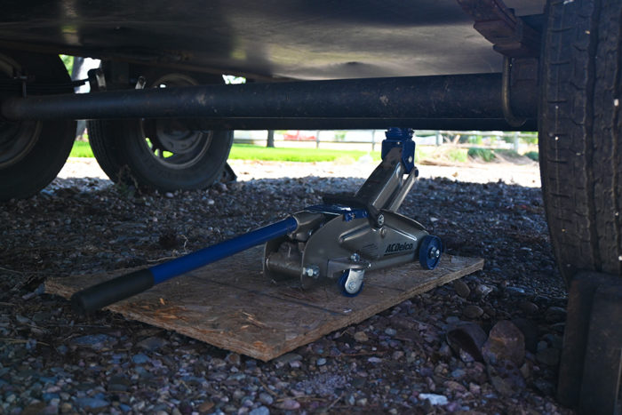 Place a floor jack and block of wood or a jack stand under the axle before you start removing the leaf spring