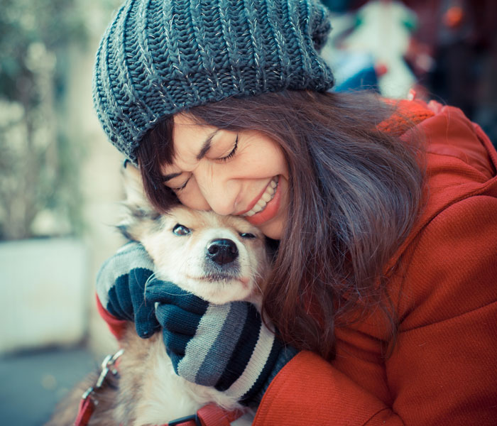 woman in winter clothes hugging a dog