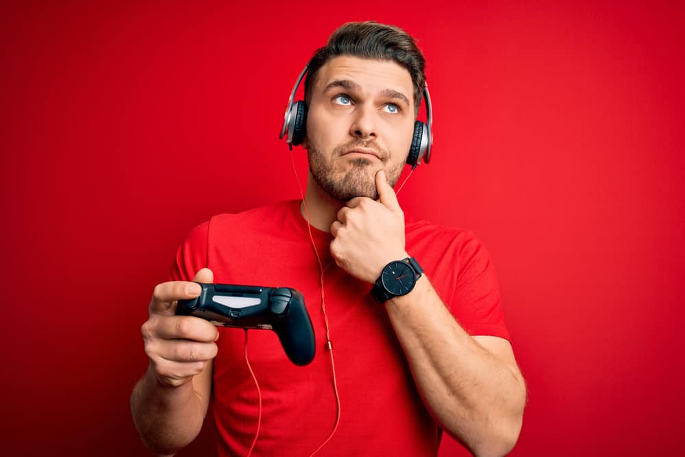 gamer man with blue eyes playing video games using gamepad joystick serious face thinking