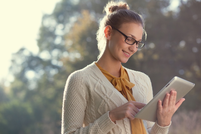 Woman in glasses and sweater with tablet