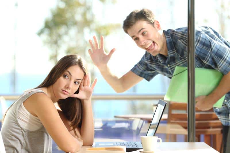 woman ignoring man waving in cafe