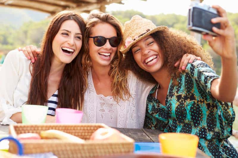 Female friends taking selfies during outdoor lunch