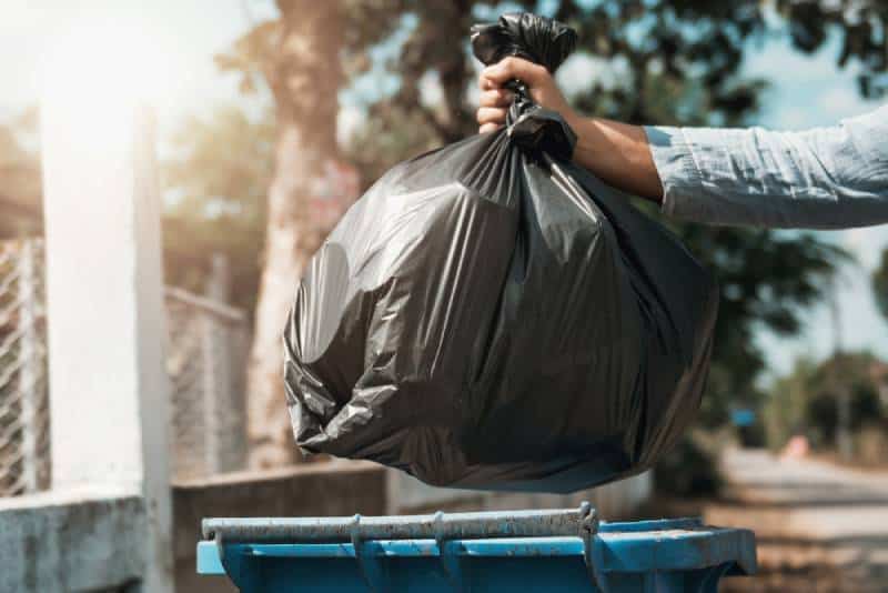 woman holding a black trash bag