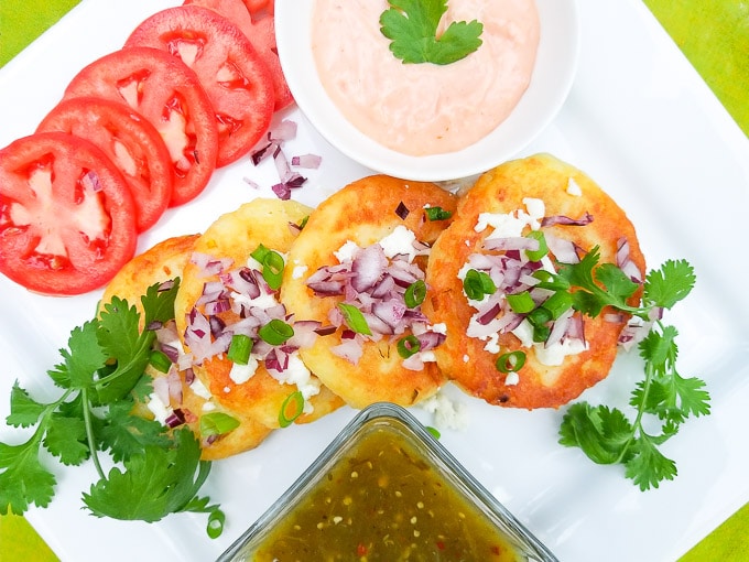 Tortitas de Papa (Fries) is served on a white plate with salsa verde and mayo.