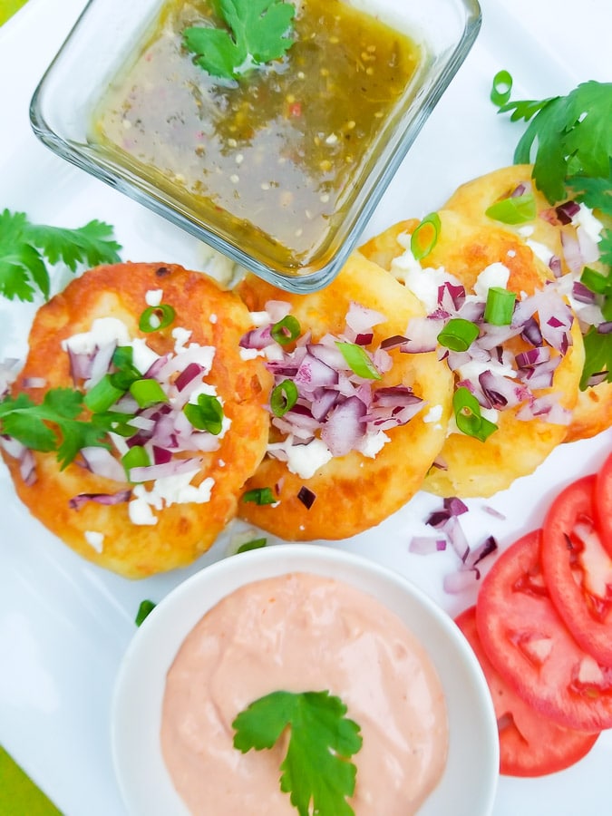 Tortitas de Papa (Fries) is served on a white plate with salsa verde and mayo.