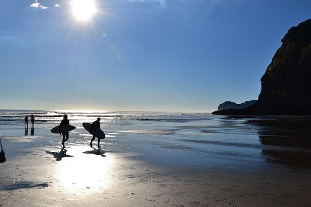 Surfers walking against the beach in Piha, West Auckland