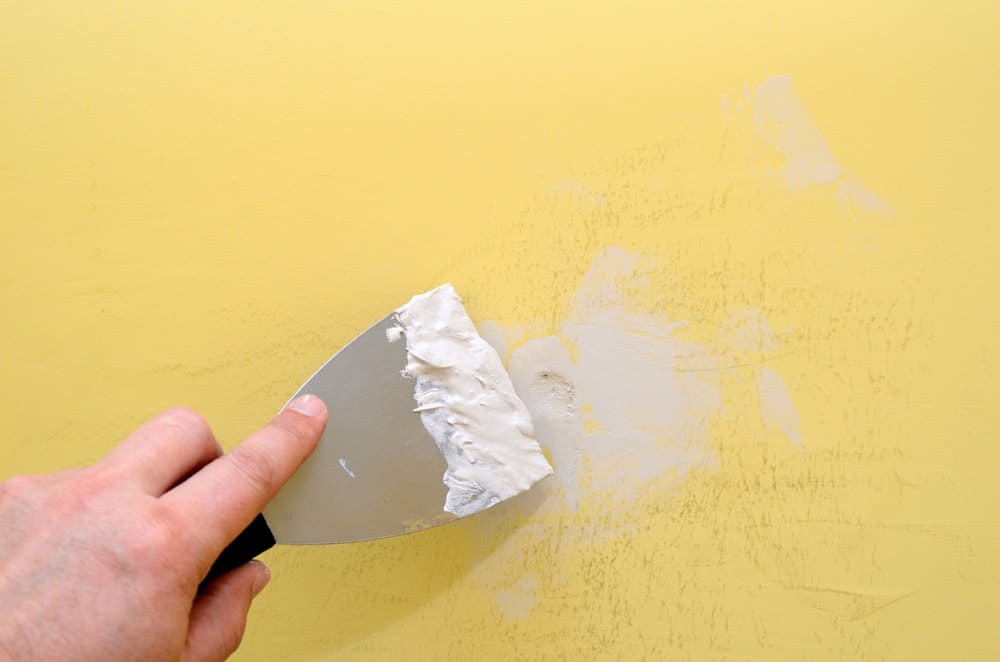 Close-up of someone removing poster stickers from the wall.