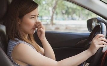 Woman holding her nose while driving