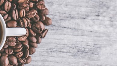 Hot coffee in a mug and coffee beans on a table