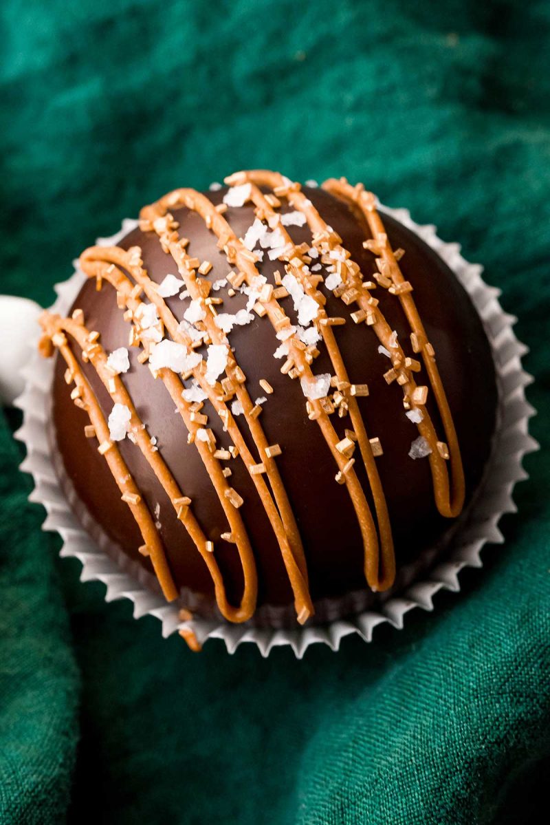Caramel sauce hot chocolate bombs dripping with caramel and topped with a layer of floating sea salt.