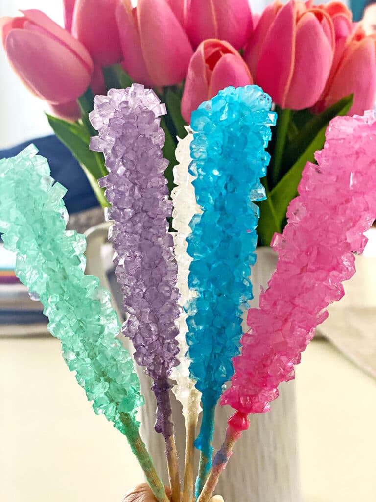Homemade rock candy on sticks with pink tulips in the background