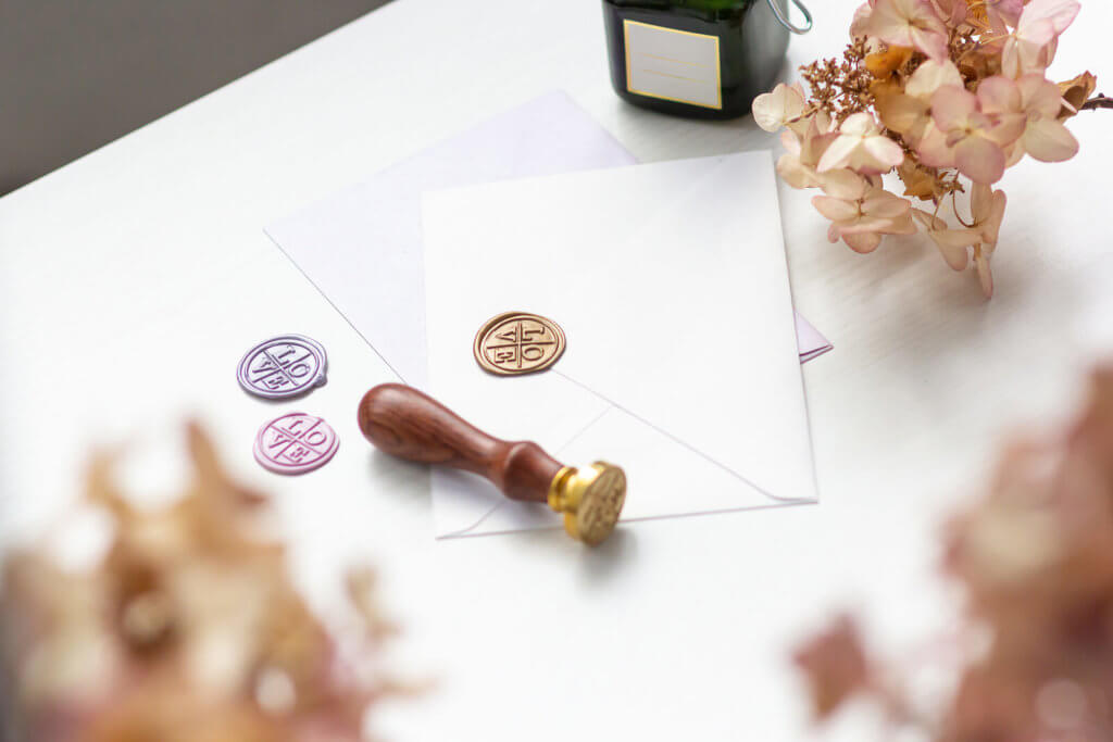 A white table with wax seal, wax seal and an envelope on it