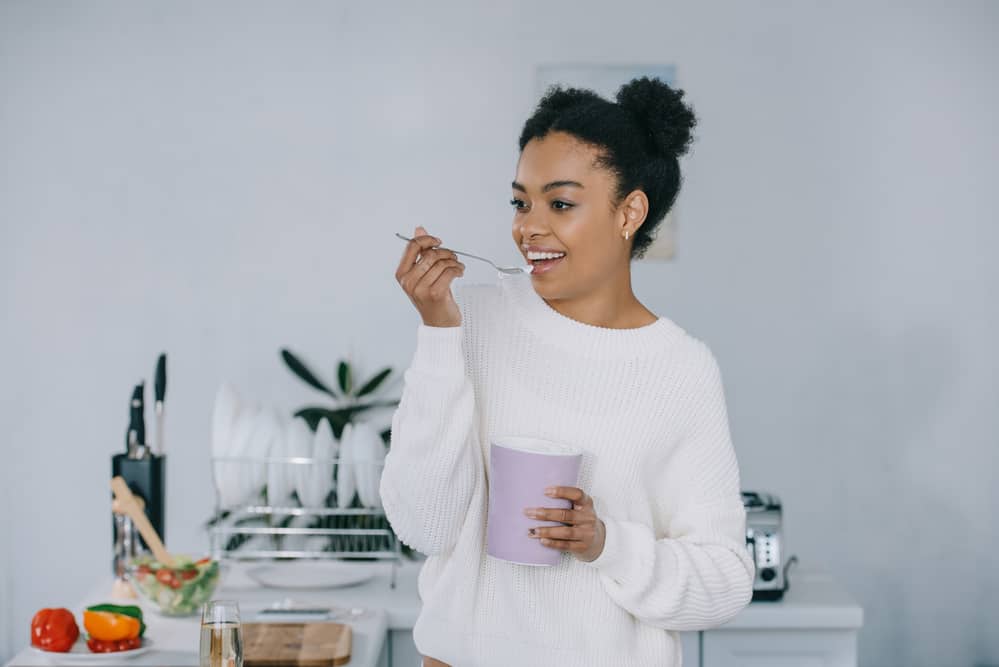 Woman wearing white sweater while eating ice cream from bowl