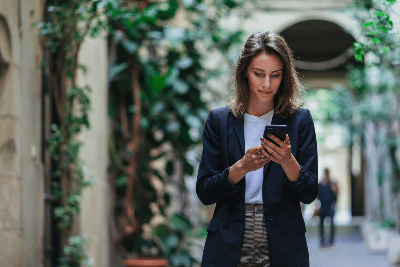 brown-haired woman standing on the street and button on the phone