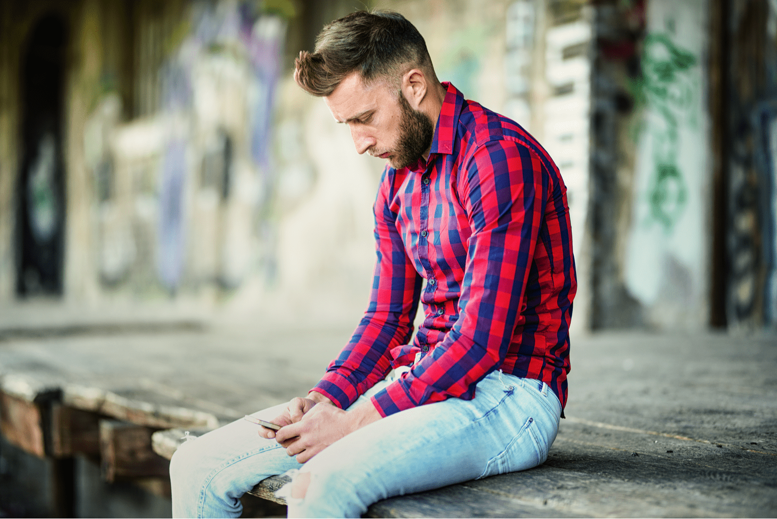 a sad man sits on the pier and buttons on the phone