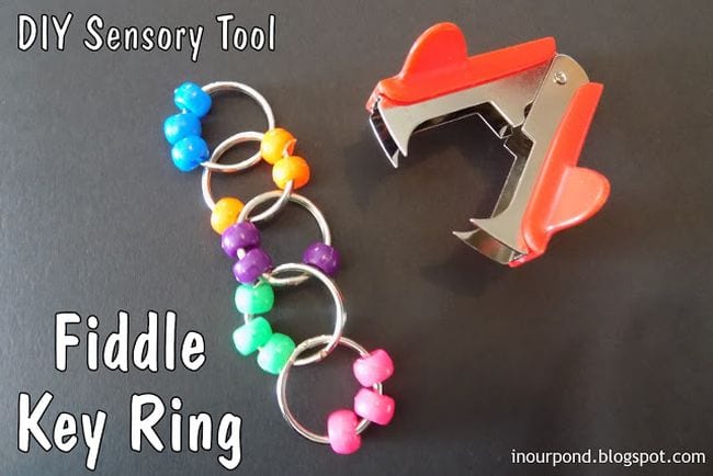 Keychain beads stick together to form a chain, next to a staple remover; Fiddle Key Ring reading text