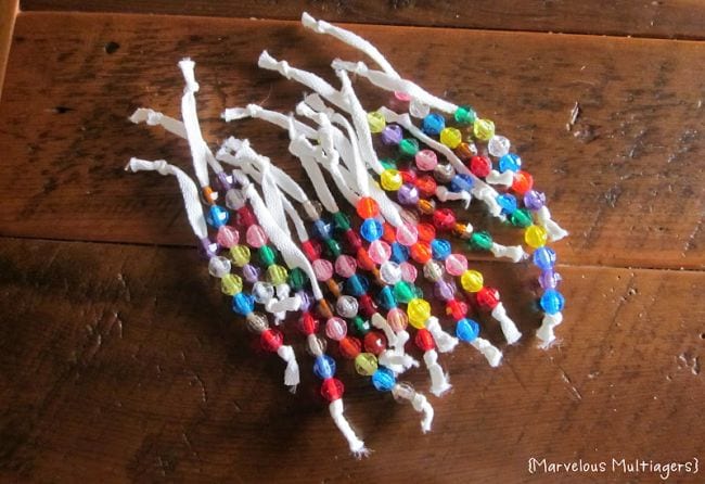 White shoelaces knotted at each end with colorful beads strung on them (DIY)