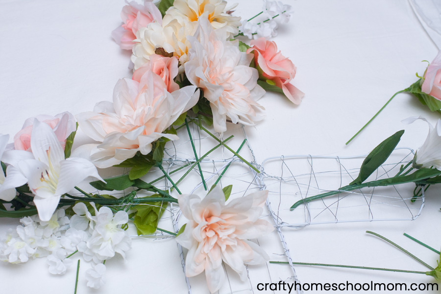 Attach the flowers to the wreath frame by knitting the stems through the wire mesh.