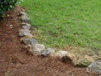 Rocks around the beds planted with pine straw.