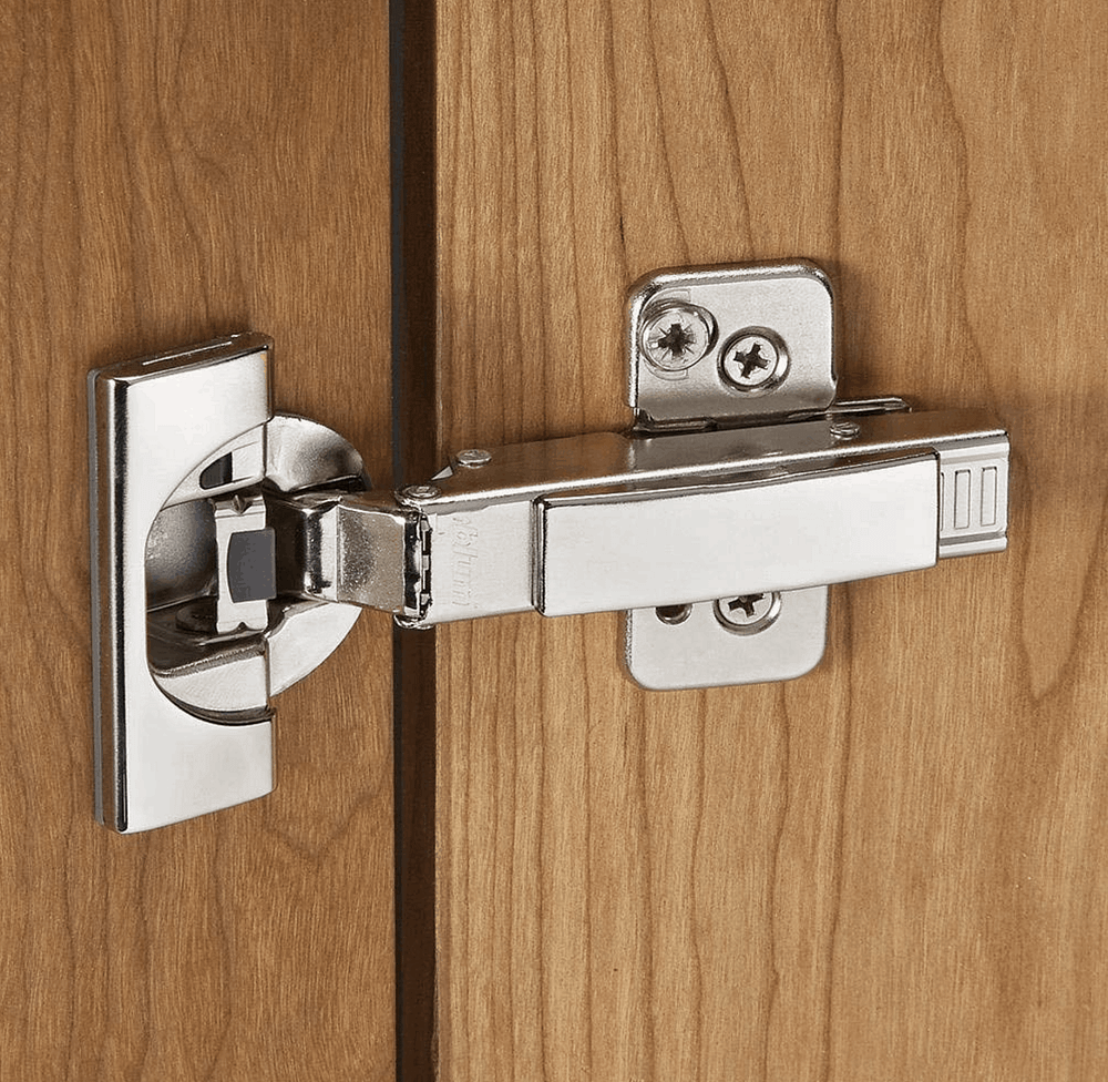 soft close hinge hardware laying on a cabinet door with a drill