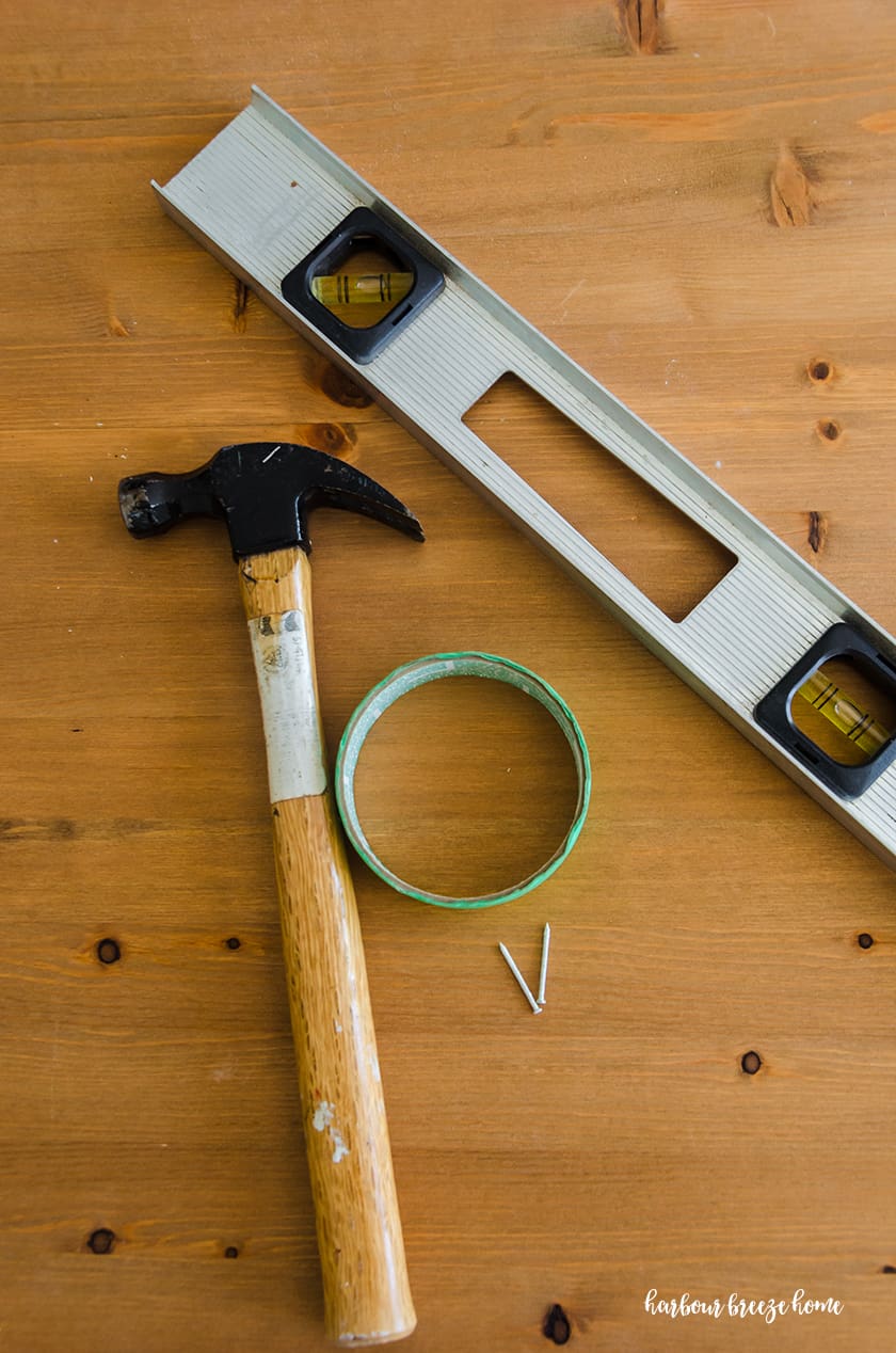Hammer, tape, nail and level - essential items to hang a picture in drywall.