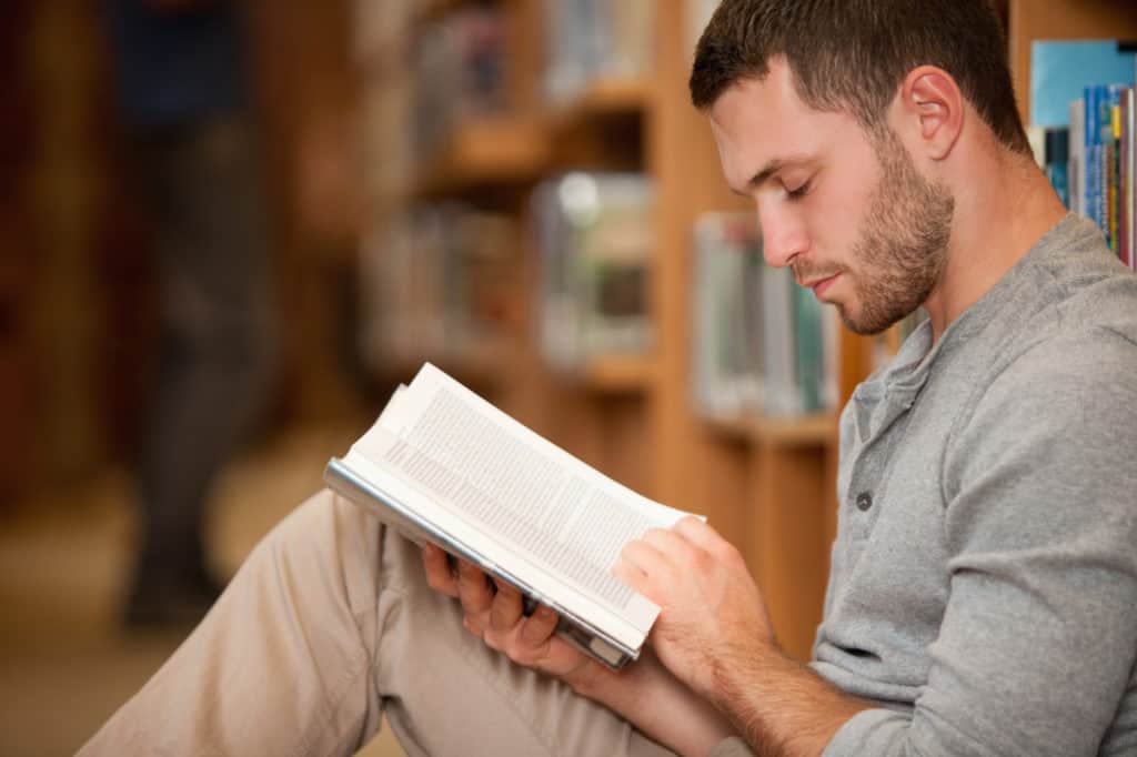 Serious male student reading a book