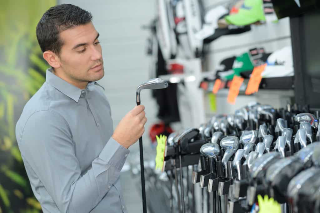 man inspecting the golf clubs