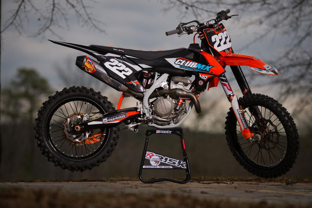 beautiful pic of a dirt bike sitting on a risk racing ats stand with an unfocused outdoor scene