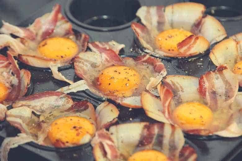 Raw eggs and bacon in muffin pans