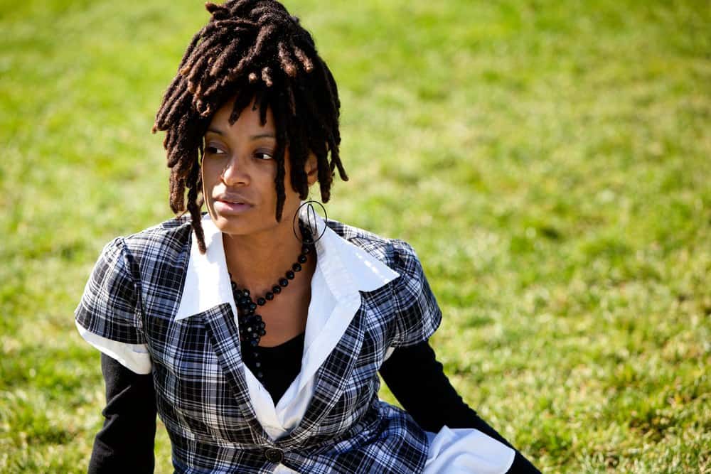 African American woman isolated on grass wearing loc extensions.