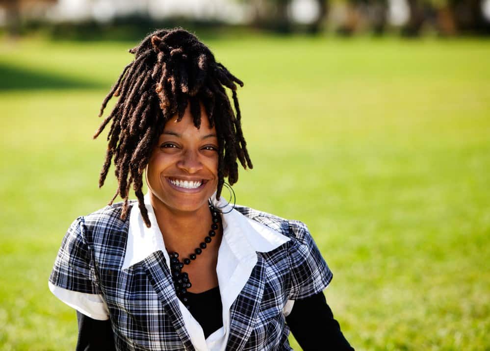 A beautiful African American with candid smile sitting in the yard of a huge lawn.